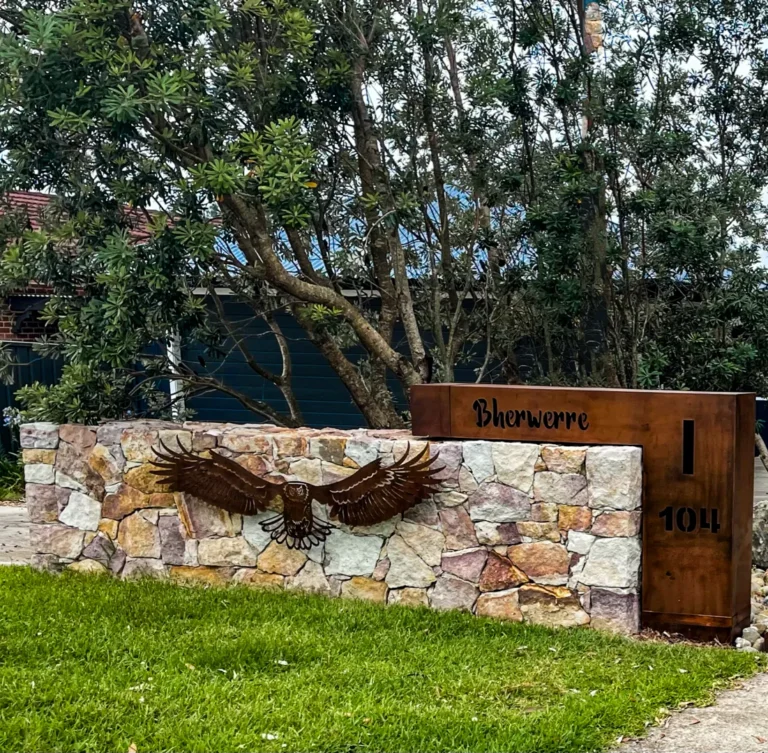 Stone wall with metal eagle sculpture outside house.