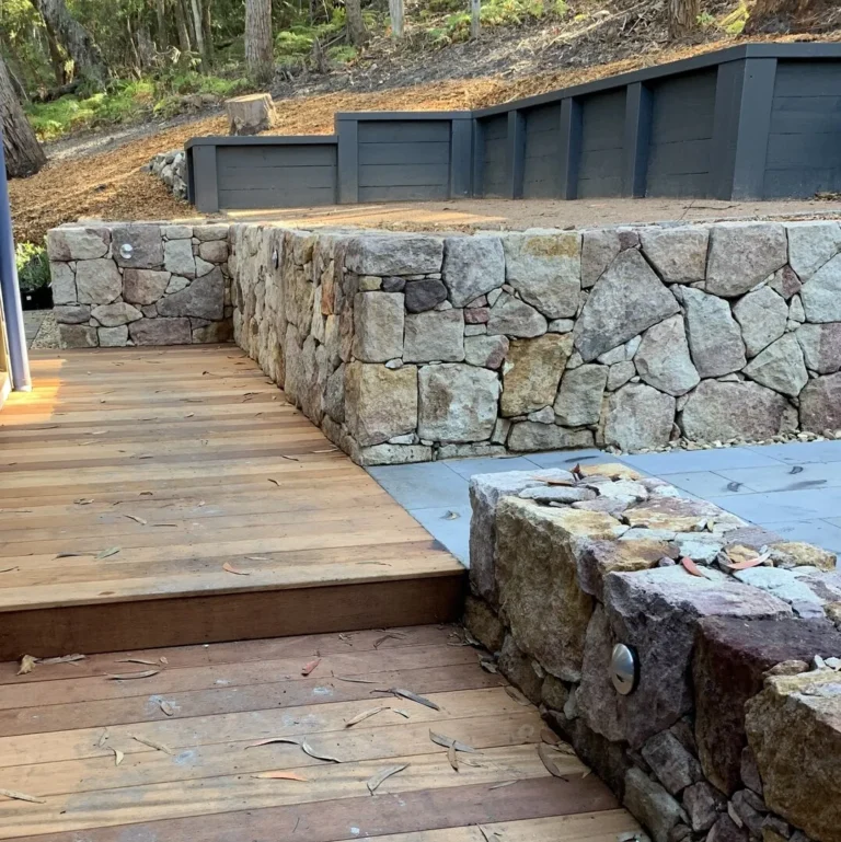 Wooden deck with stone retaining wall in backyard.