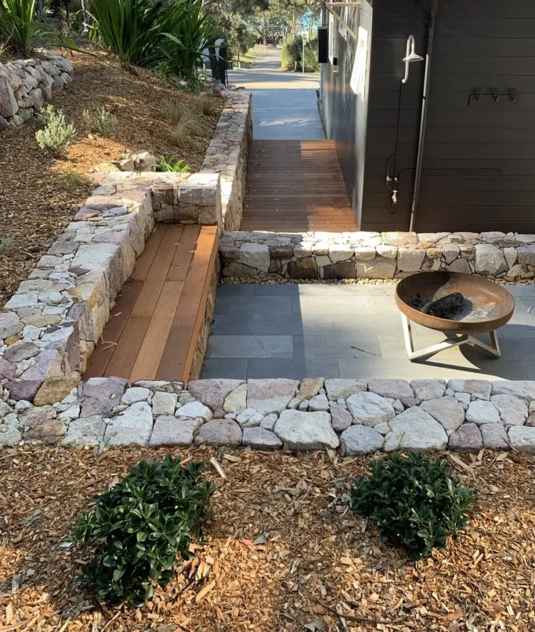 Outdoor seating area with fire pit and stone wall.