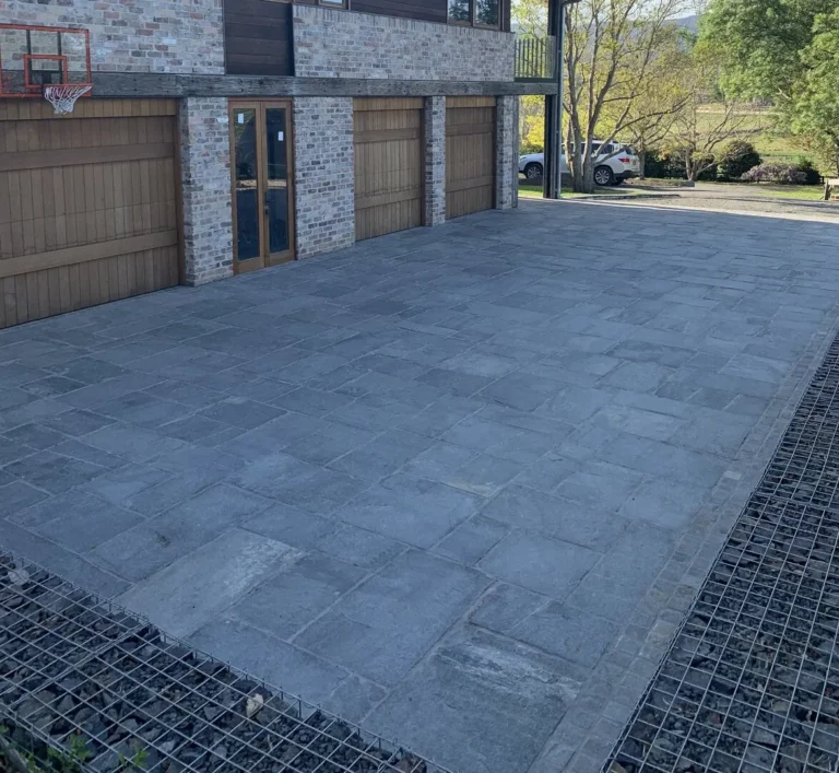 Spacious driveway with stone tiles and basketball hoop.