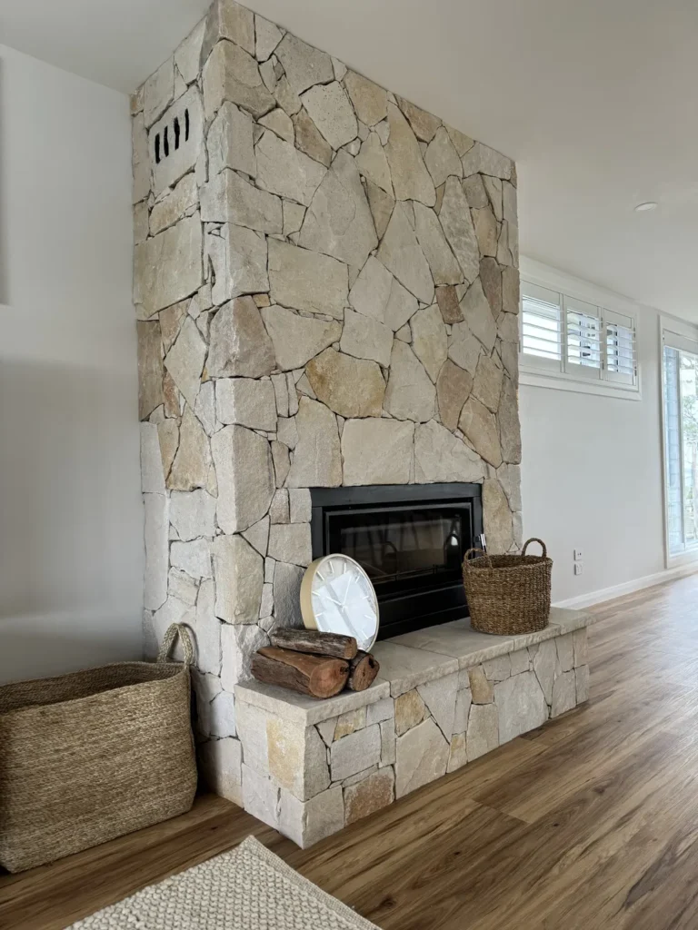 Stone fireplace with baskets, wood, and clock decor.