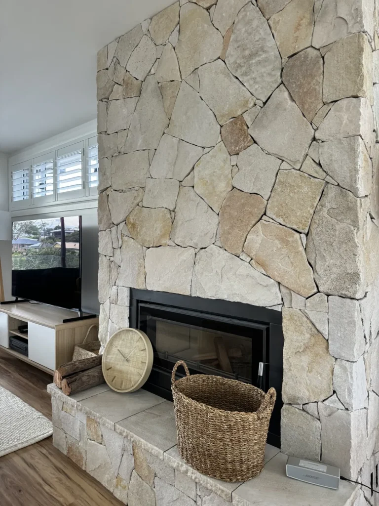 Rustic stone fireplace with wicker basket and clock.