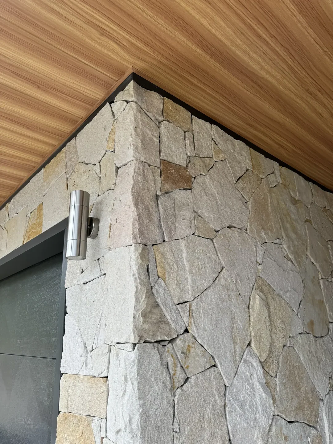 Modern stone and wood wall with metal light fixture.