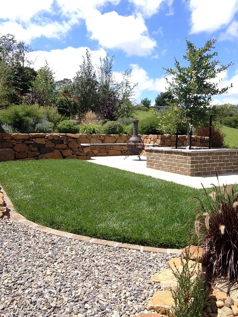 Beautiful backyard with lawn, plants, and stone landscaping.