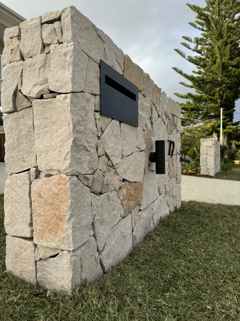 Stone wall with mailbox and house number.