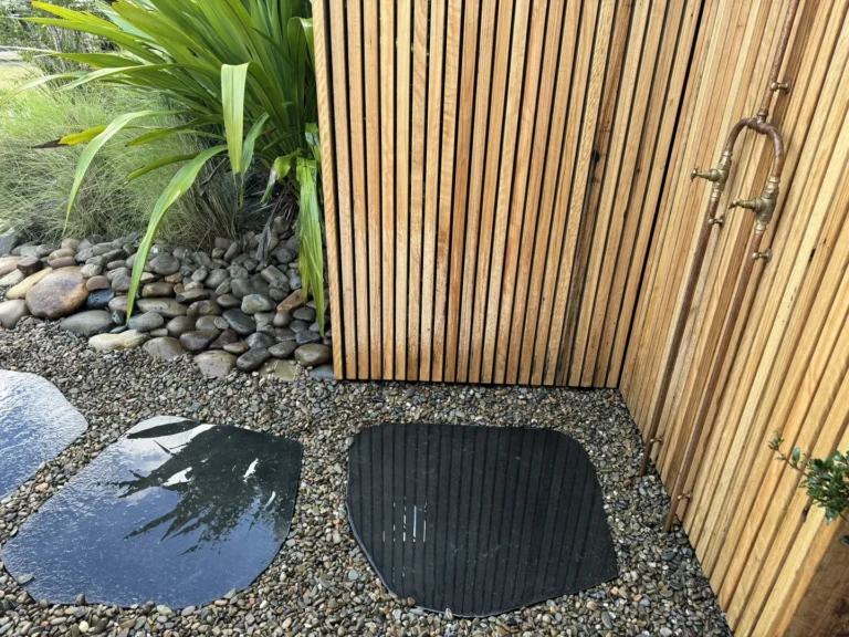 Outdoor shower with stone path and wooden wall