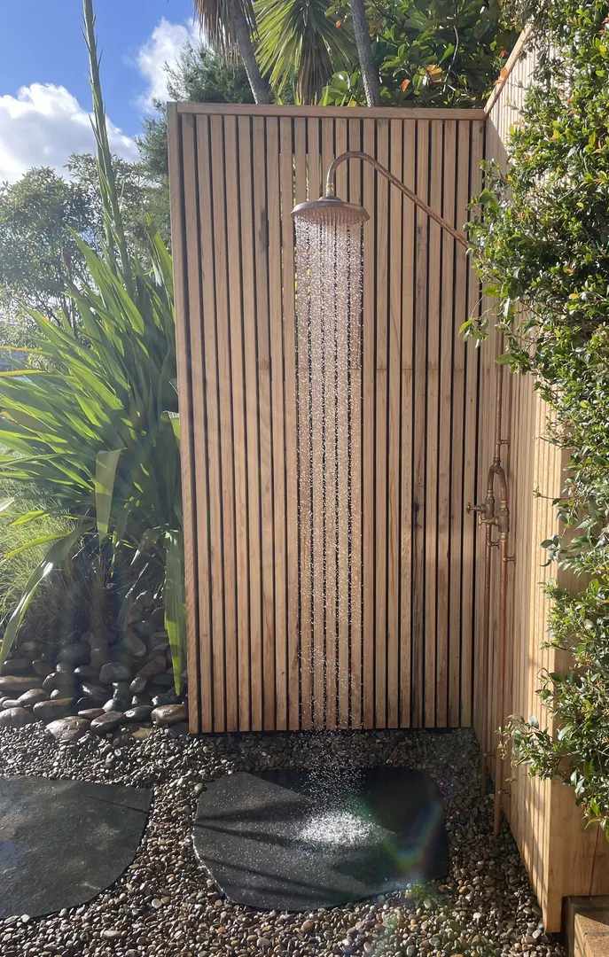 Outdoor wooden shower with plants and stones