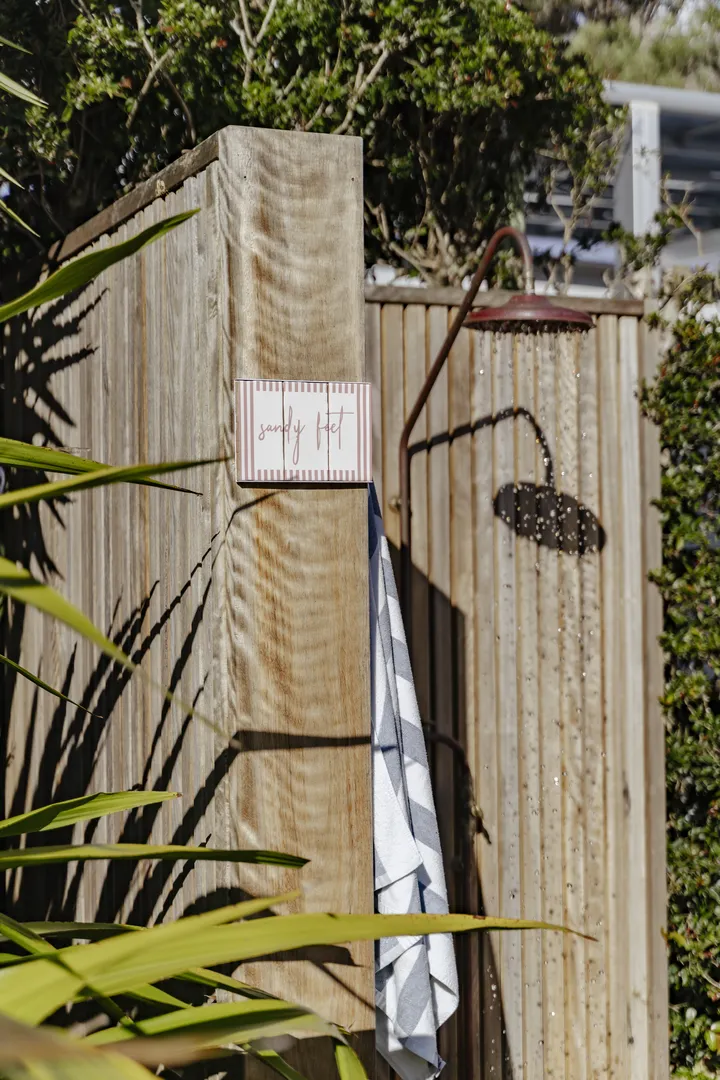 Outdoor wooden shower with sandy feet sign