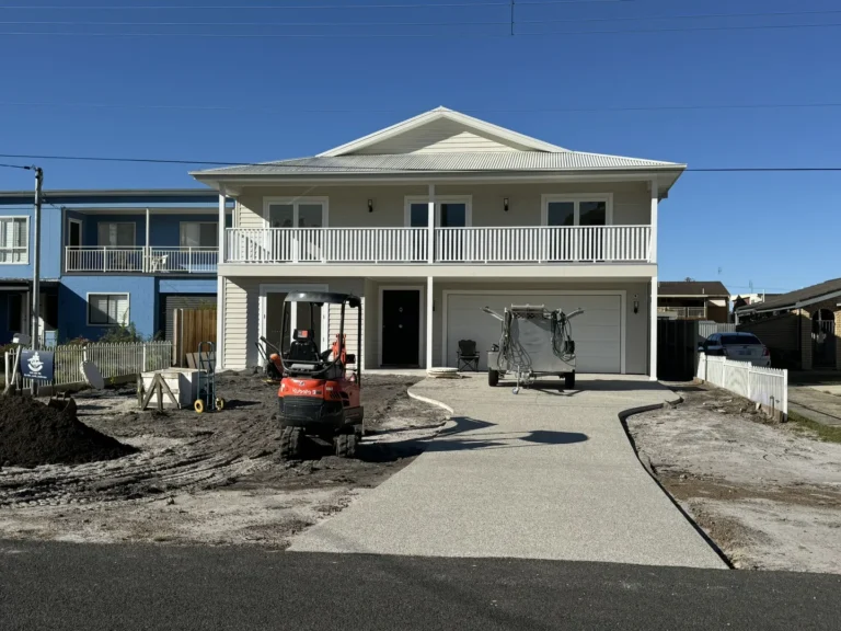 House under construction with equipment in front yard.