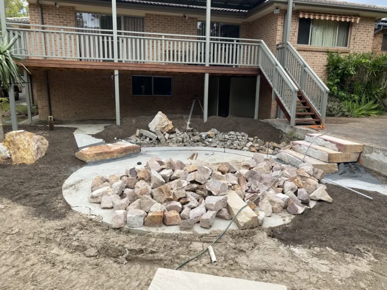 Backyard patio construction with rocks and soil piles.