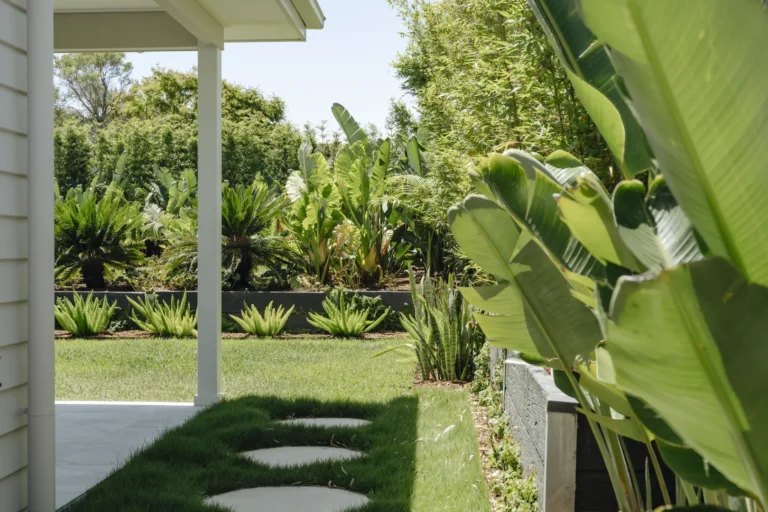 Lush tropical backyard garden beside modern patio