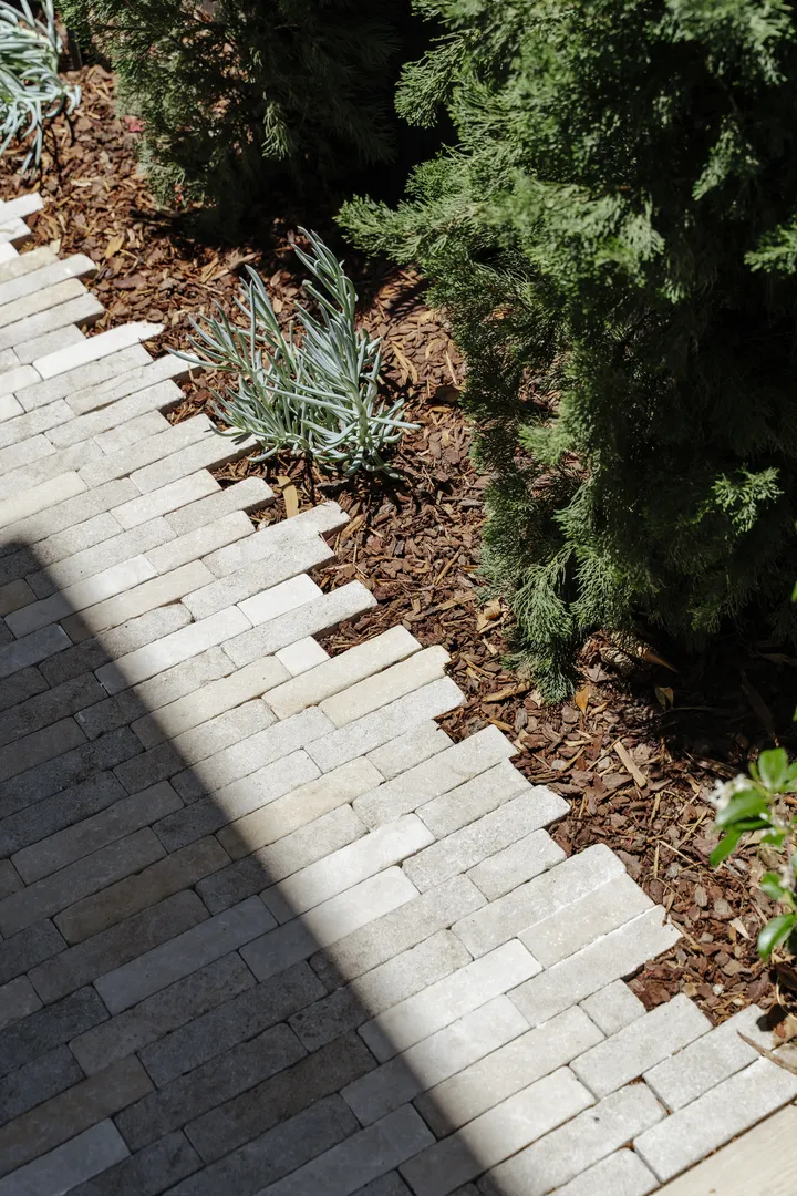 Stone paver walkway beside mulched garden bed