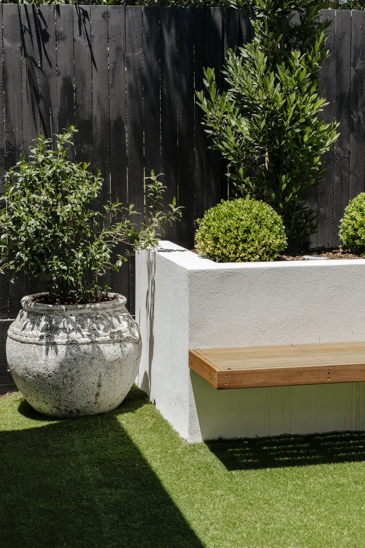 Modern backyard with planter, bench, and potted plant