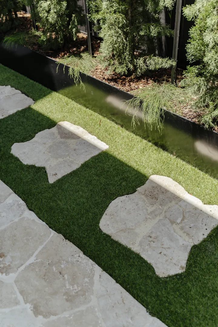Stone stepping path beside narrow garden water feature