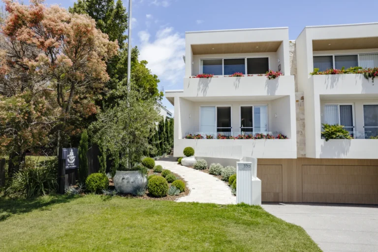 Modern white two-story home with landscaped garden